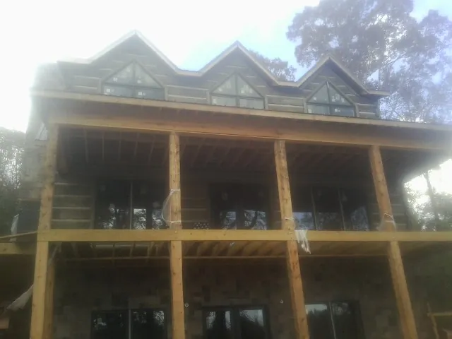 Dormers and porch framing on a large log home under construction — Roof Coating work by our crew in Bedford